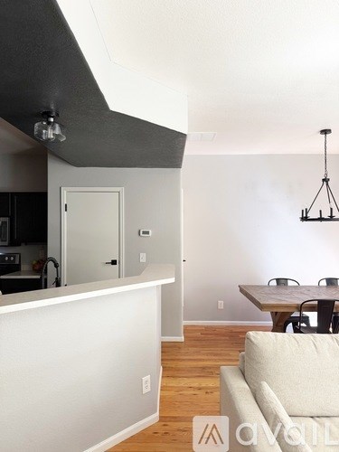 A modern kitchen with a white counter and a dining table with chairs.