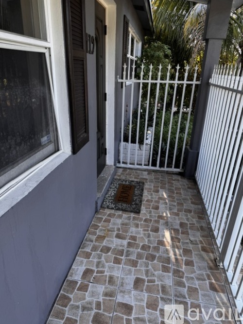 A white fence and a tiled walkway lead to a door.