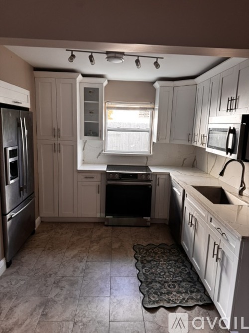 A kitchen with white cabinets and a black fridge.