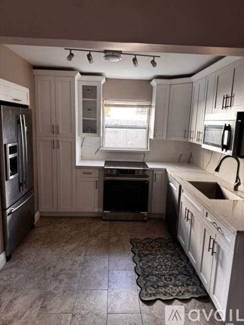 A kitchen with white cabinets and a black fridge.