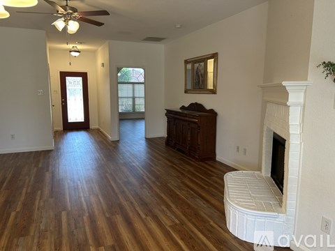 A living room with wood floors and a fireplace.