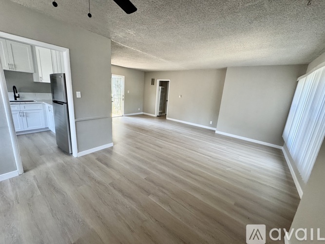 A spacious room with wooden flooring and a ceiling fan.