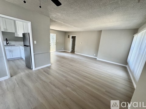A spacious room with wooden flooring and a ceiling fan.