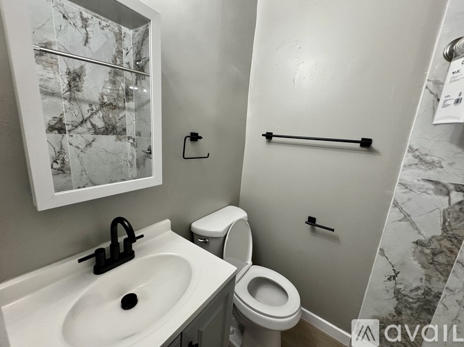 A bathroom with a toilet, sink, and a marble wall.