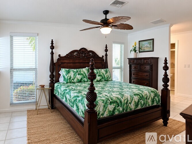 A bedroom with a large bed and a ceiling fan.