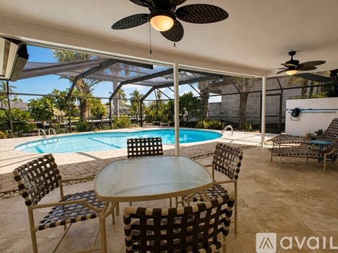 A patio with a table, chairs, and a pool.