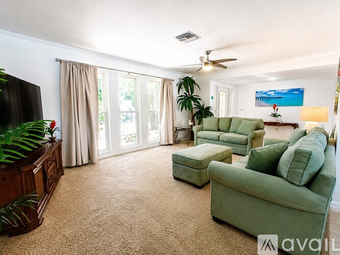 A living room with a green couch and a ceiling fan.