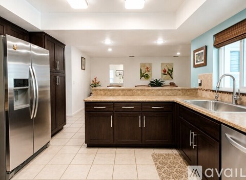A kitchen with a refrigerator, sink, and cabinets.