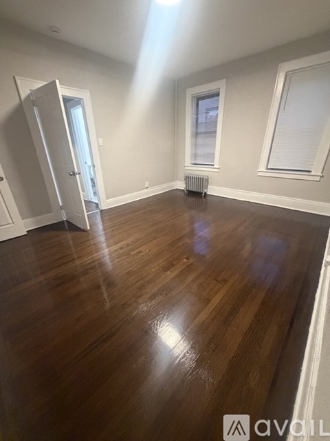 A room with wooden floors and a window with blinds.