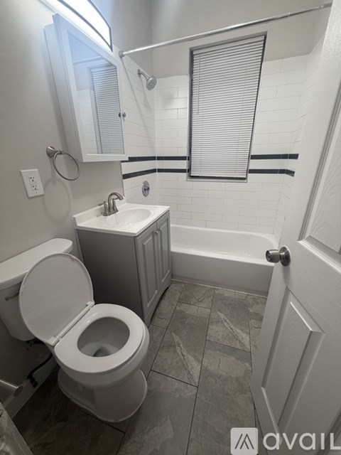 A bathroom with a toilet, sink, and a window.