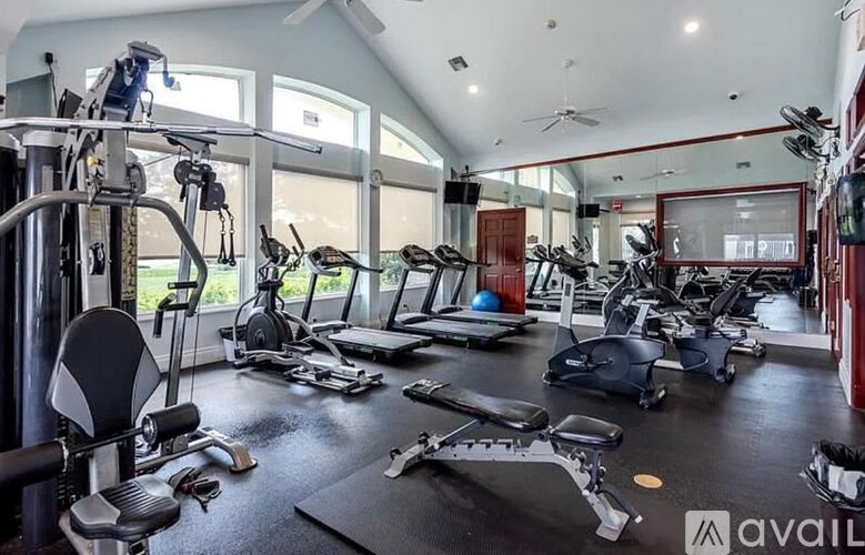 A well-equipped gym with various exercise machines and a large mirrored wall.
