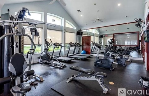 A well-equipped gym with various exercise machines and a large mirrored wall.