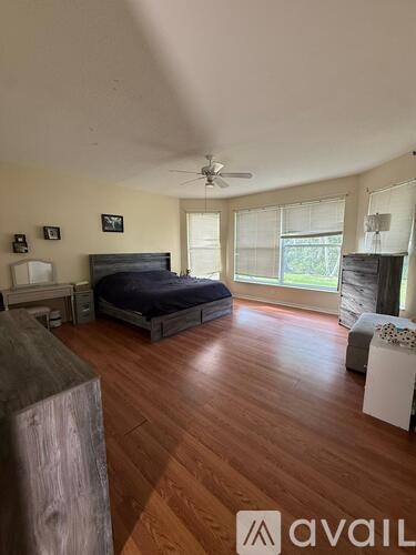 A bedroom with a bed, dresser, and ceiling fan.