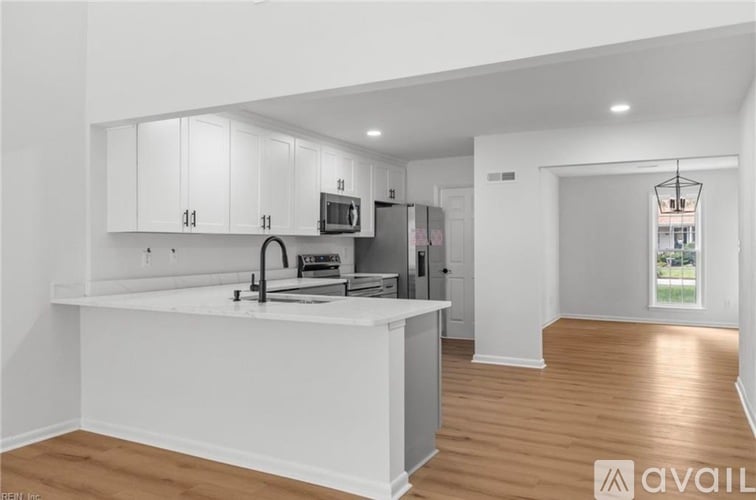 A kitchen with white cabinets and a wooden floor.