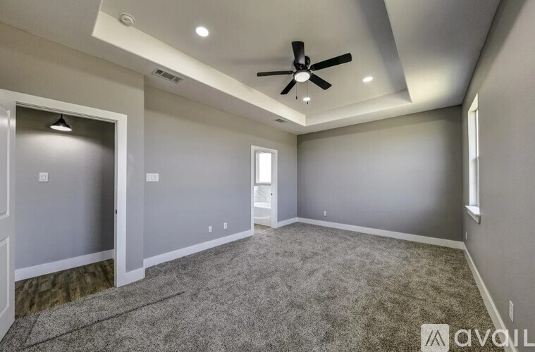 A spacious room with a ceiling fan and carpeted floor.