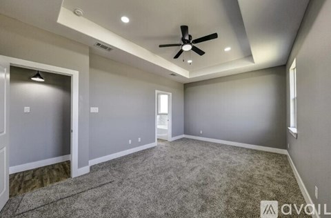 A spacious room with a ceiling fan and carpeted floor.