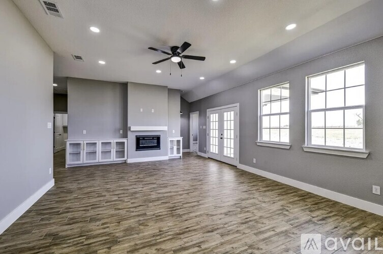 A spacious living room with a fireplace and a ceiling fan.