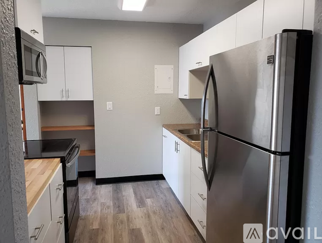 A kitchen with a refrigerator, microwave, and oven.