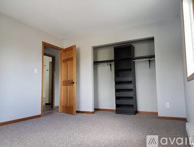 A room with a wooden door and a black shelf unit.