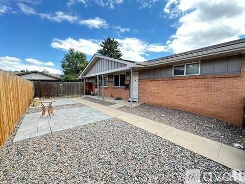 A backyard with a gravel patio and a wooden fence.