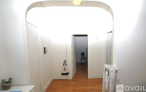 A room with a white wall and a doorway leading to another room.