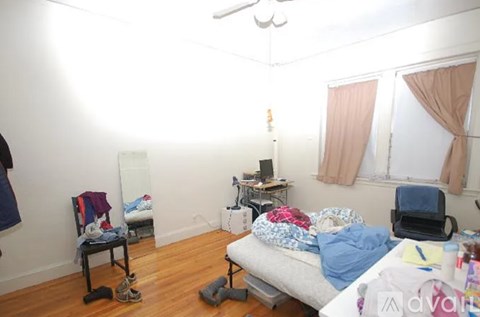 A messy bedroom with a bed, chair, and desk.