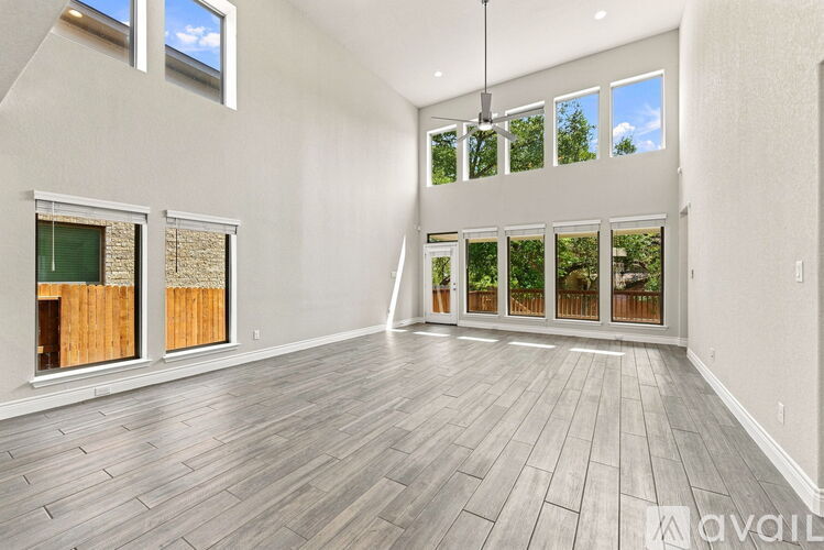 A spacious room with wooden flooring and large windows.