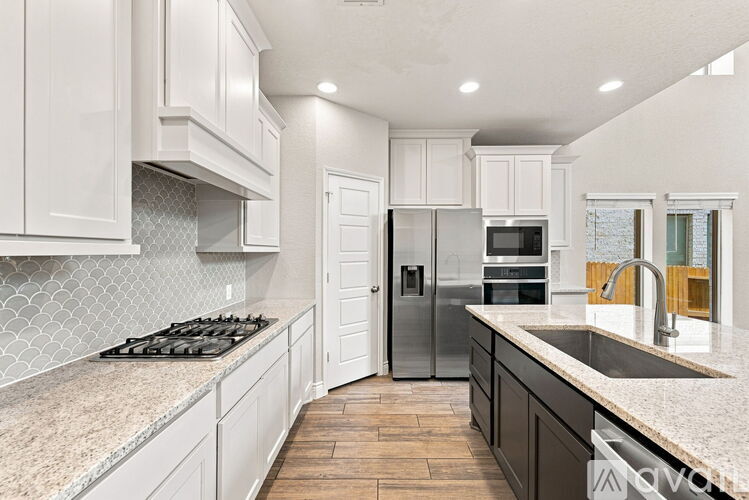 A kitchen with white cabinets and a black stove top.