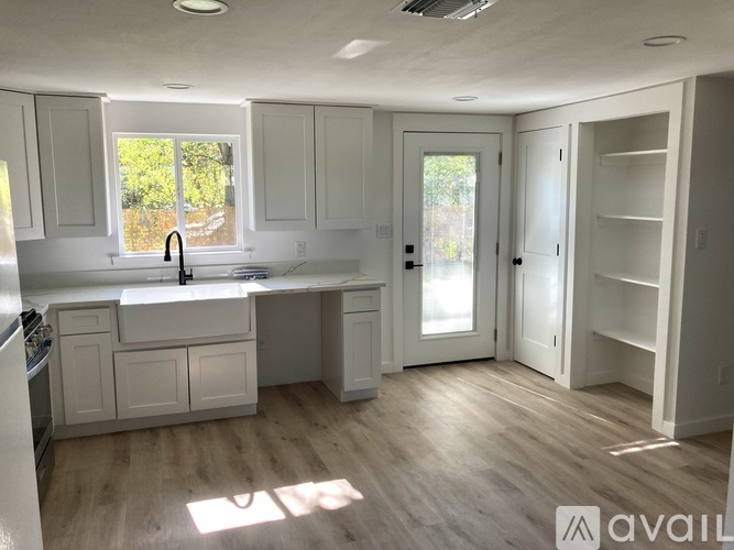 A kitchen with white cabinets and a wooden floor.