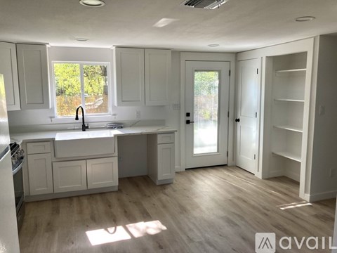 A kitchen with white cabinets and a wooden floor.