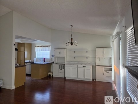 A large open kitchen and living room with wooden floors and white walls.