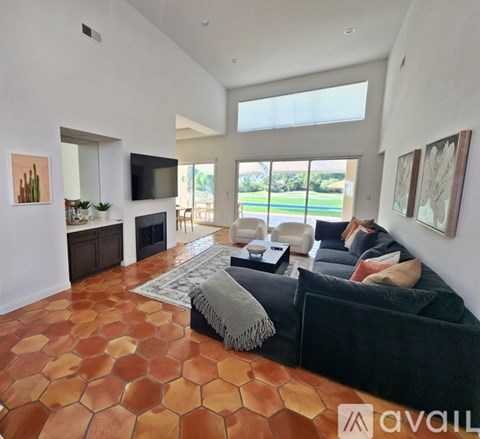 A living room with a black couch and a wooden floor.