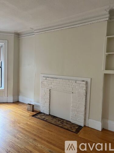 A white fireplace in a room with wooden floors and white walls.