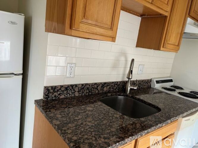 A kitchen with a granite countertop and wooden cabinets.