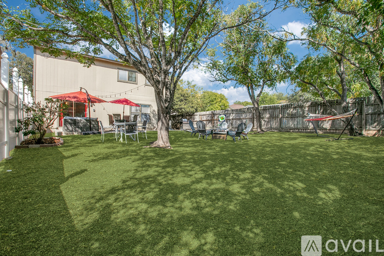 A backyard with a lawn, trees, and a patio area.