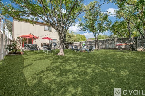 A backyard with a lawn, trees, and a patio area.