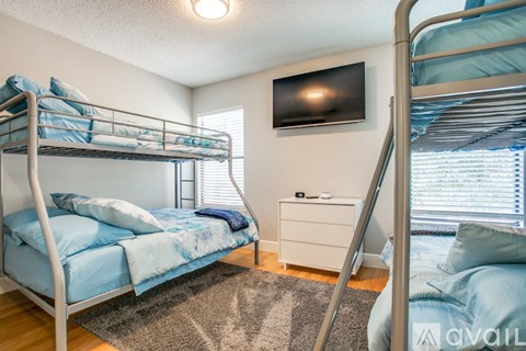 A bedroom with two bunk beds and a flat screen TV mounted on the wall.