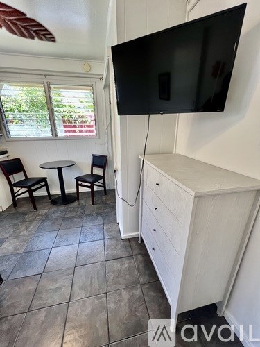 A black screen on a television hangs on a wall above a white cabinet.