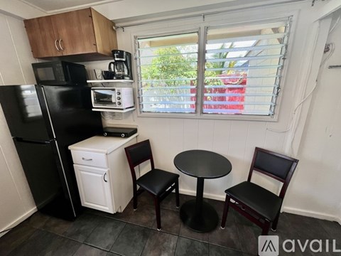 A kitchen with a black fridge, white dishwasher, and a black table with two chairs.