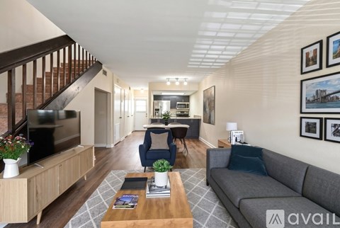 A living room with a couch, a coffee table, and a staircase.
