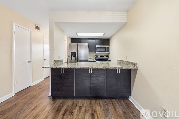 A kitchen with a black countertop and wooden flooring.