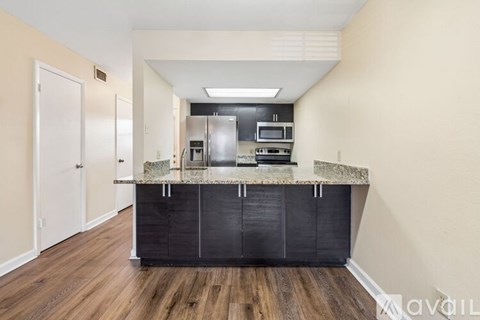 A kitchen with a black countertop and wooden flooring.