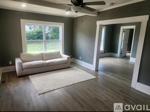 A living room with a white couch and a rug in front of a window.