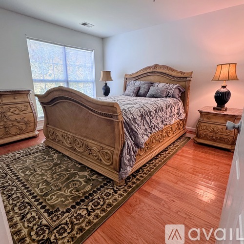 A bedroom with a large bed and two lamps.