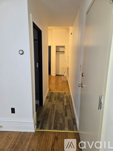 A hallway with a wooden floor and white walls.