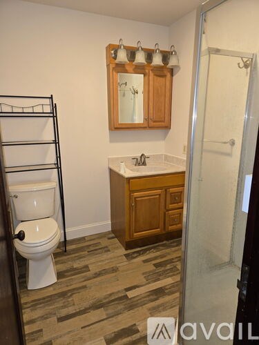 A bathroom with a toilet, sink, and mirror.