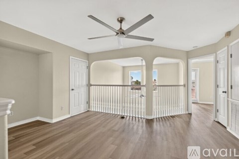 A spacious room with a ceiling fan and wooden flooring.