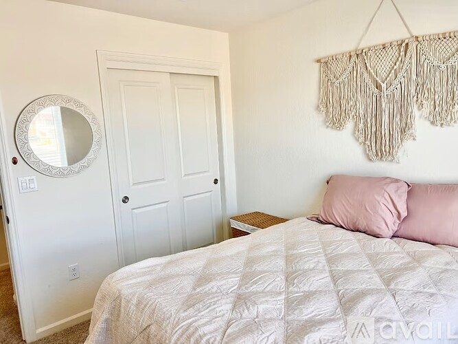 A bedroom with a bed, a mirror, and a wall hanging.