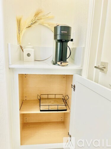 A coffee maker is on a shelf next to a plant.