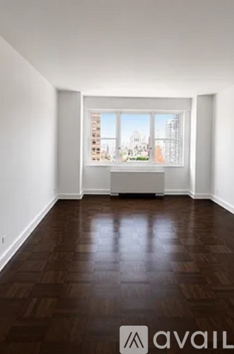 A room with wooden floors and a large window overlooking a cityscape.